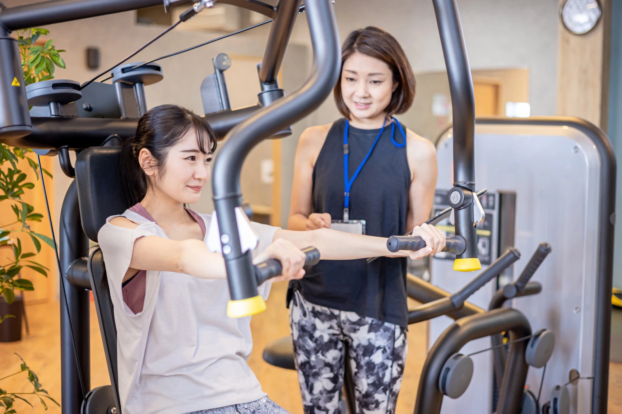 「ヘルスケア」のイメージ_トレーナーの指導のもと、トレーニングしている女性