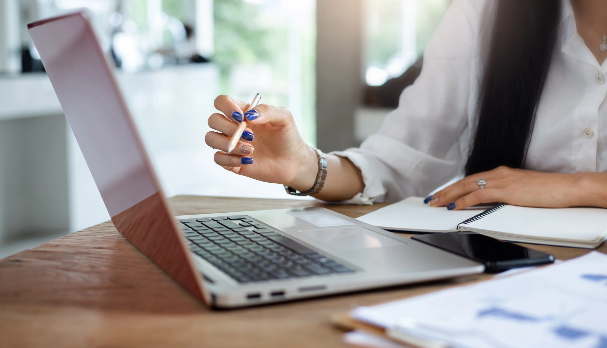 「計算」のイメージ_パソコンを見ながらノートにメモをとる女性