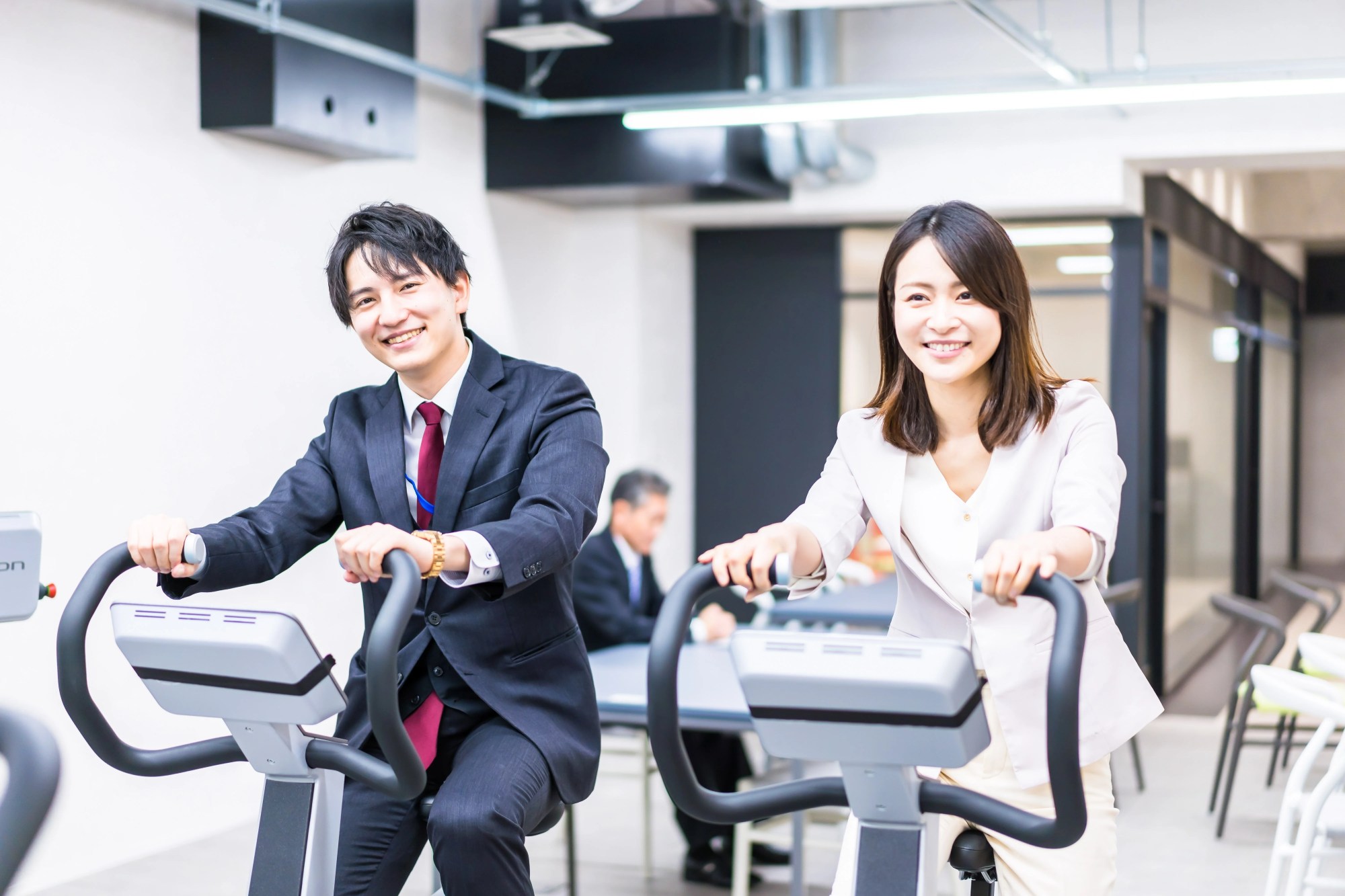 「健康経営」のイメージ_笑顔でランニングマシンを漕いでいる男性社員と女性社員