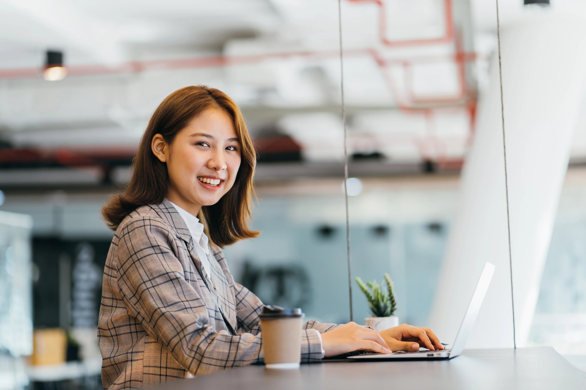 「ソリューション」のイメージ_パソコンを操作しながらこちらを見ている女性