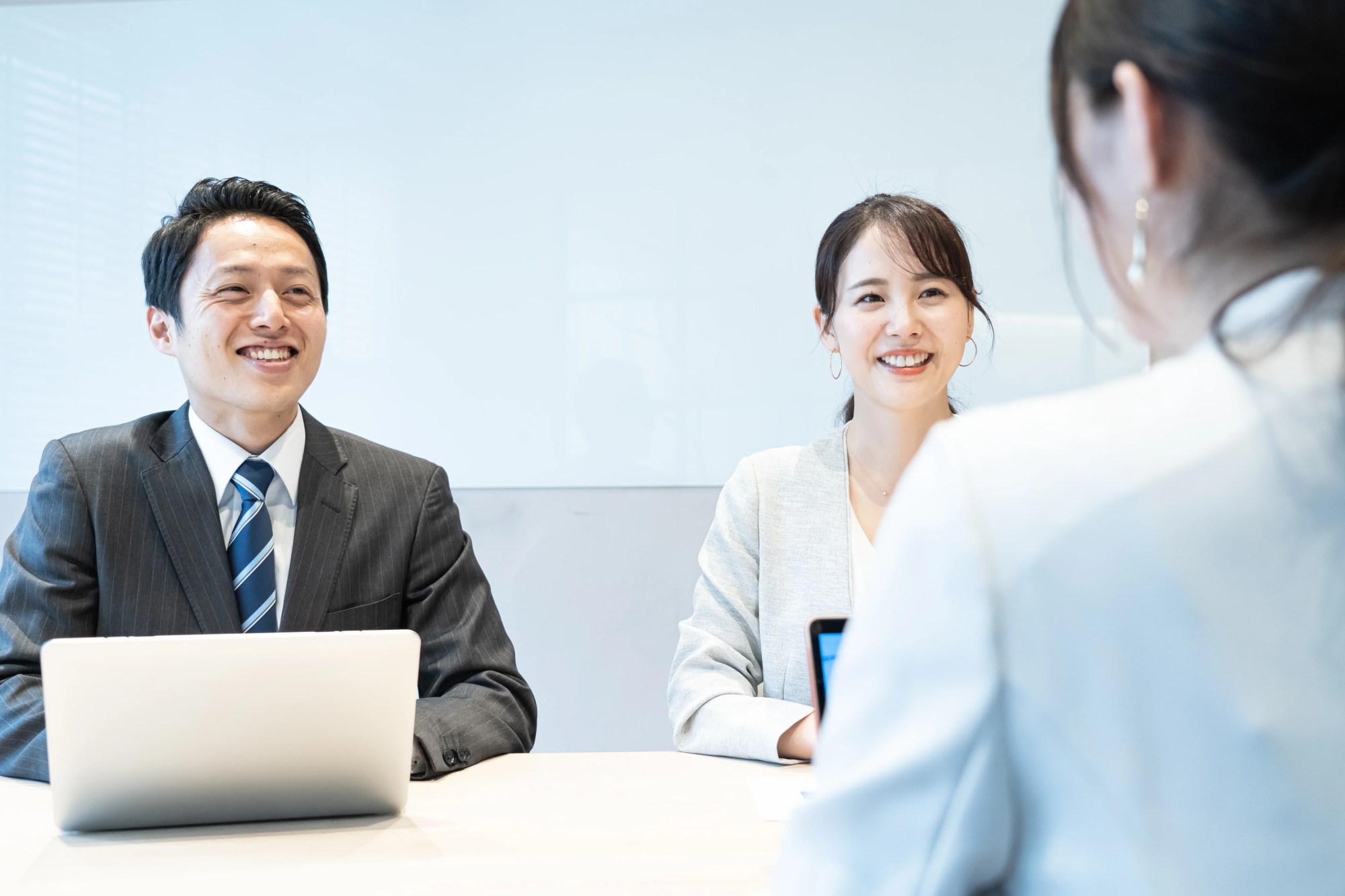 「円滑なコミュニケーション」のイメージ_笑顔で話をしている3名の社員