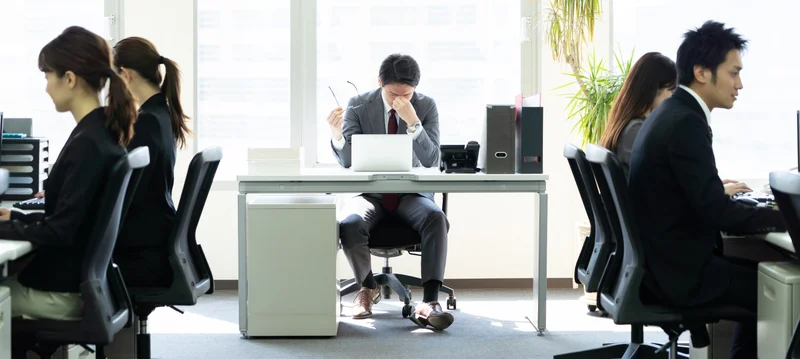 「働きすぎ」のイメージ_デスクで目頭を押さえる男性管理職