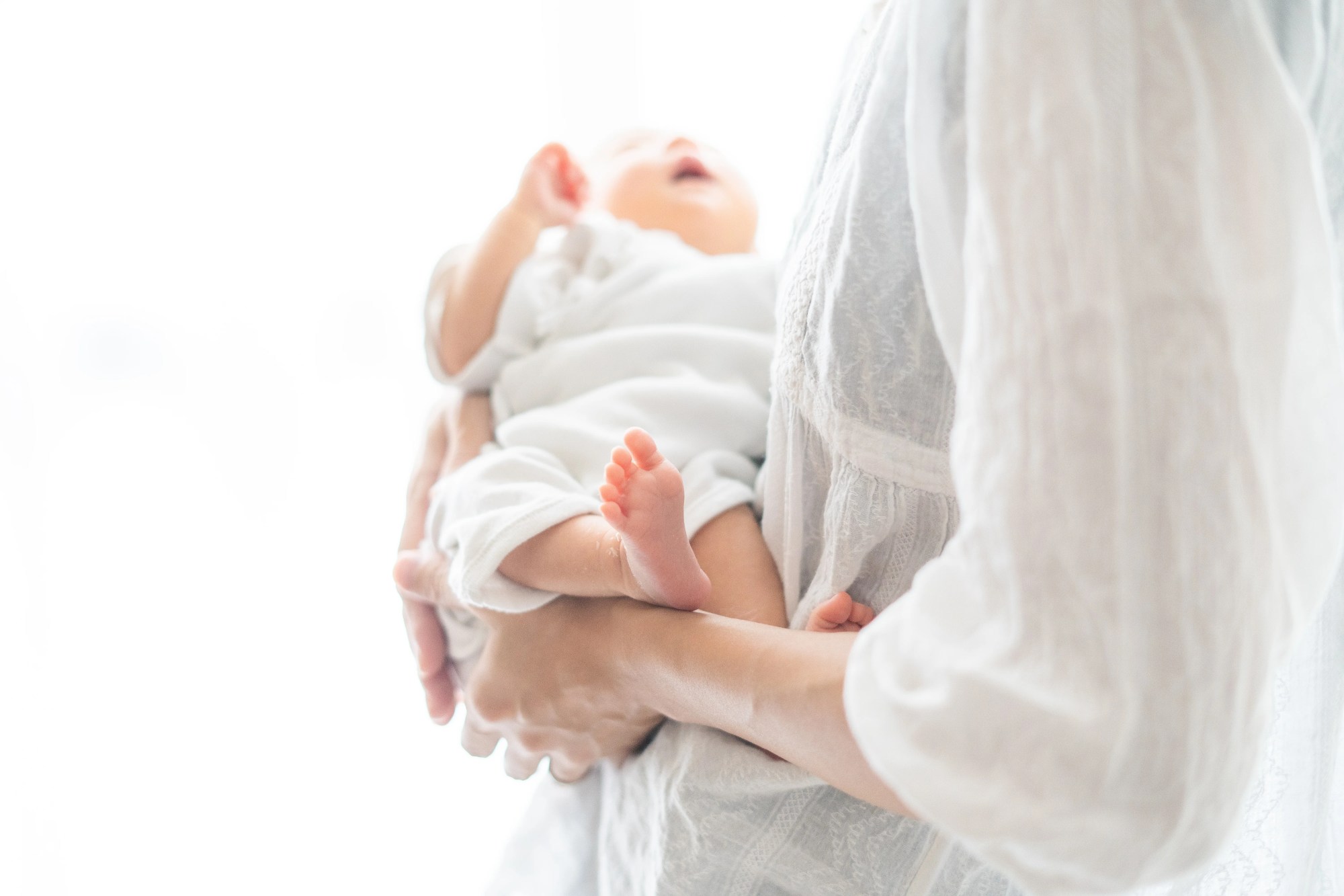 「育休」のイメージ_赤ちゃんを抱っこするお母さんの手元