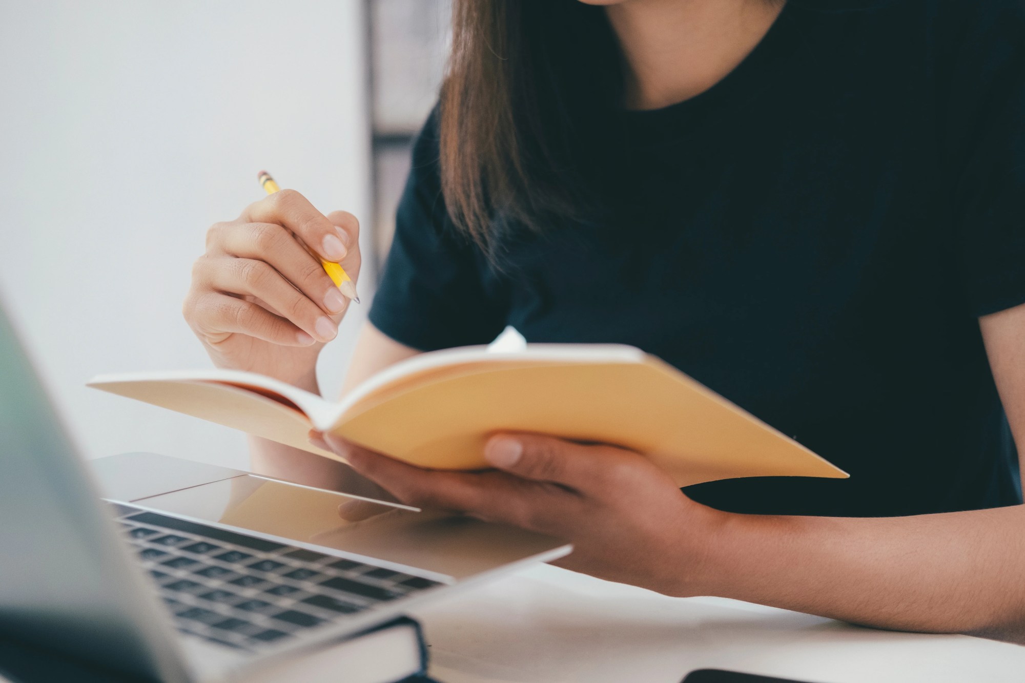 「勉強」のイメージ_ノートに目をとっている女性の手元
