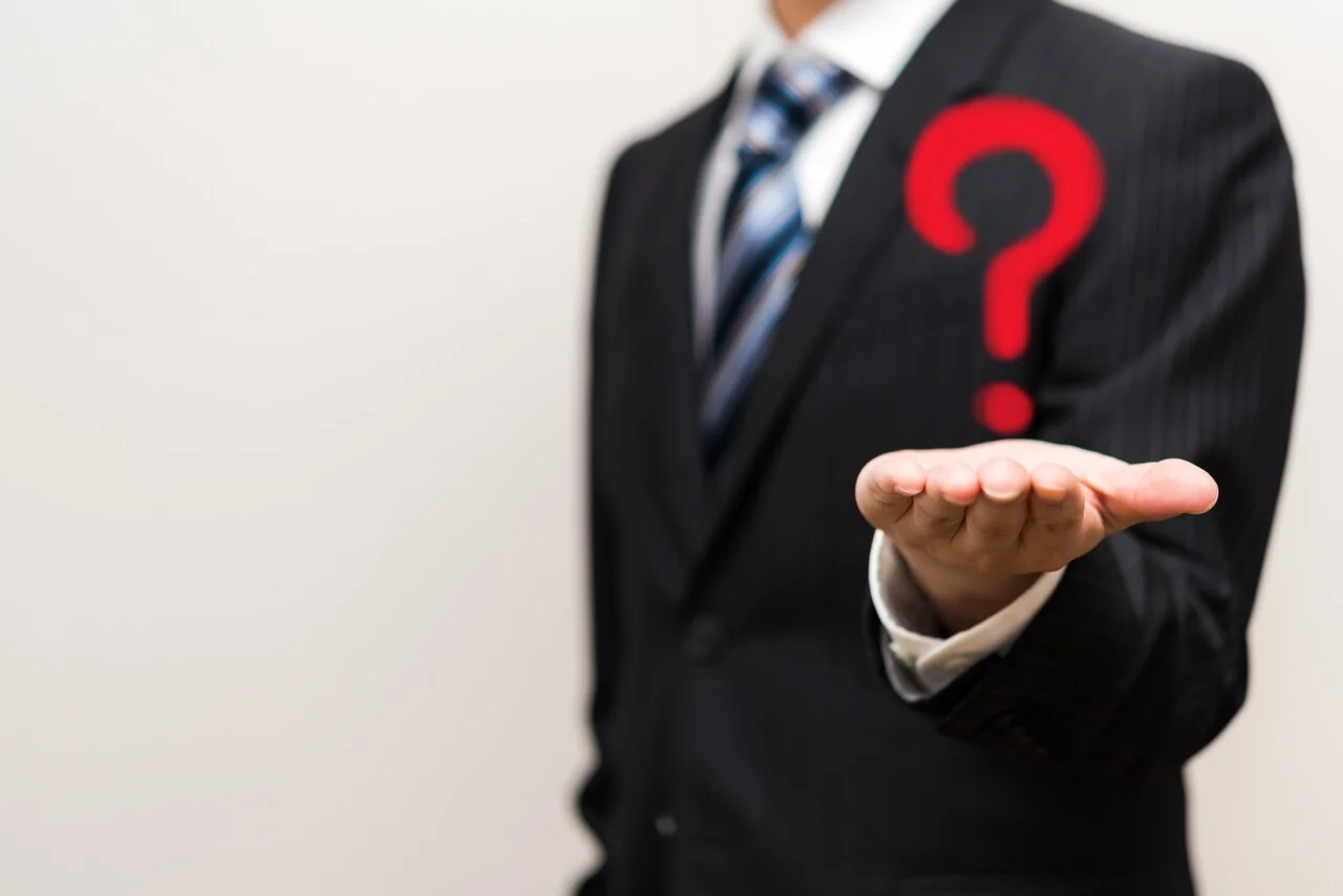 「問い」のイメージ_男性が手の上にクエスチョンマークを浮かべている様子