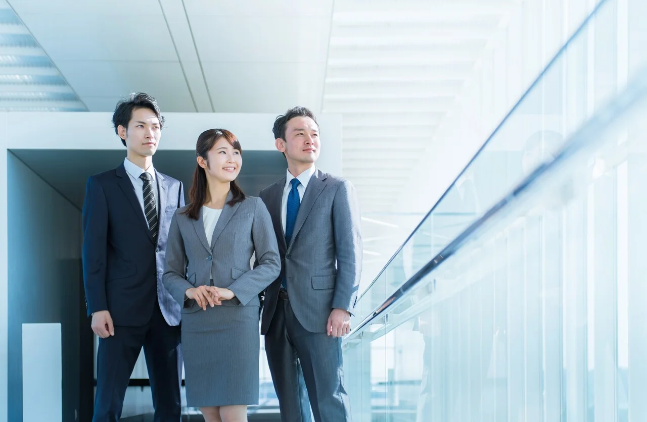 「ソリューション」のイメージ_笑顔で斜め上を見ている1名の女性社員と2名の男性社員