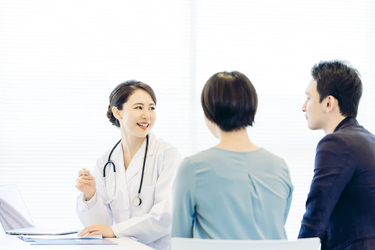 「診療」のイメージ_笑顔で話をしている医師と、話を聞く夫婦