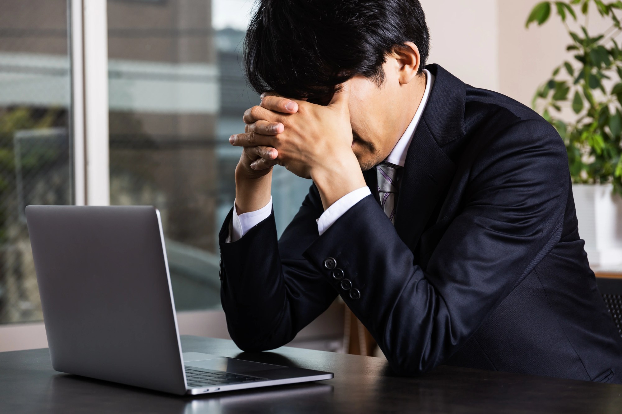 「疲労」のイメージ_パソコンの前で顔を覆い俯く男性