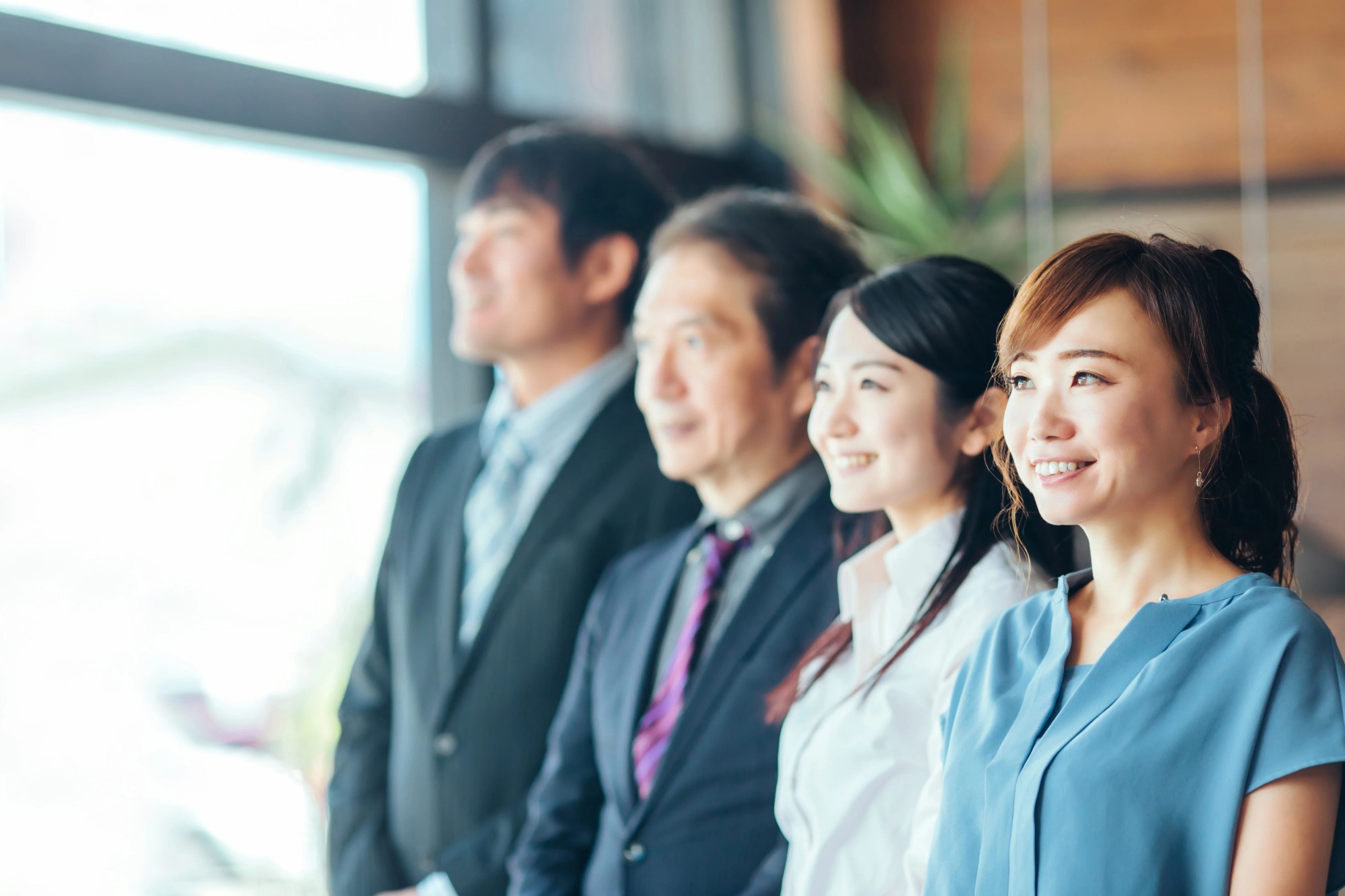 「課題解決」のイメージ_笑顔で窓の外を眺める4名の男女