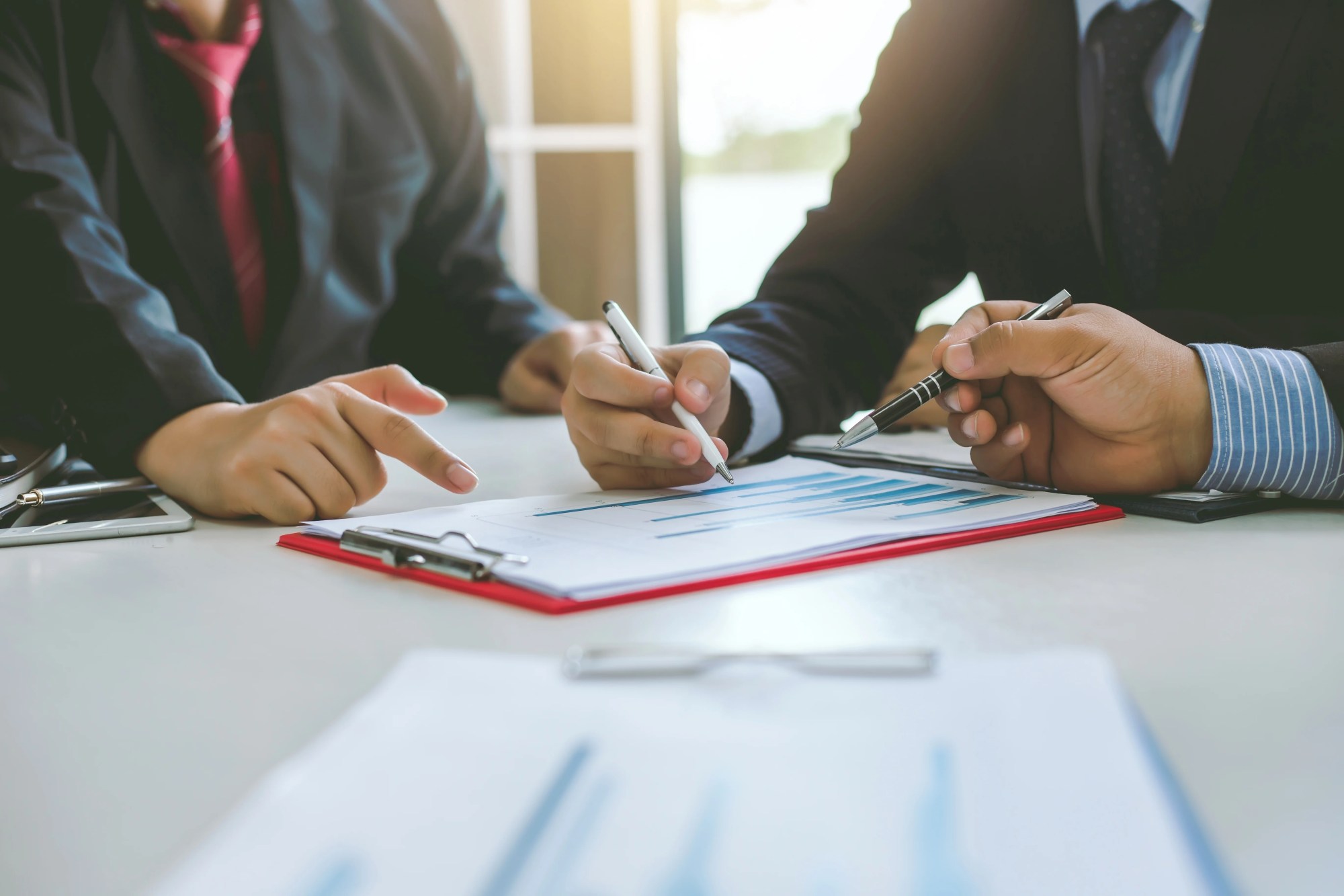 「解決策」のイメージ_グラフを元に真剣に話をしている3名の男性の手元