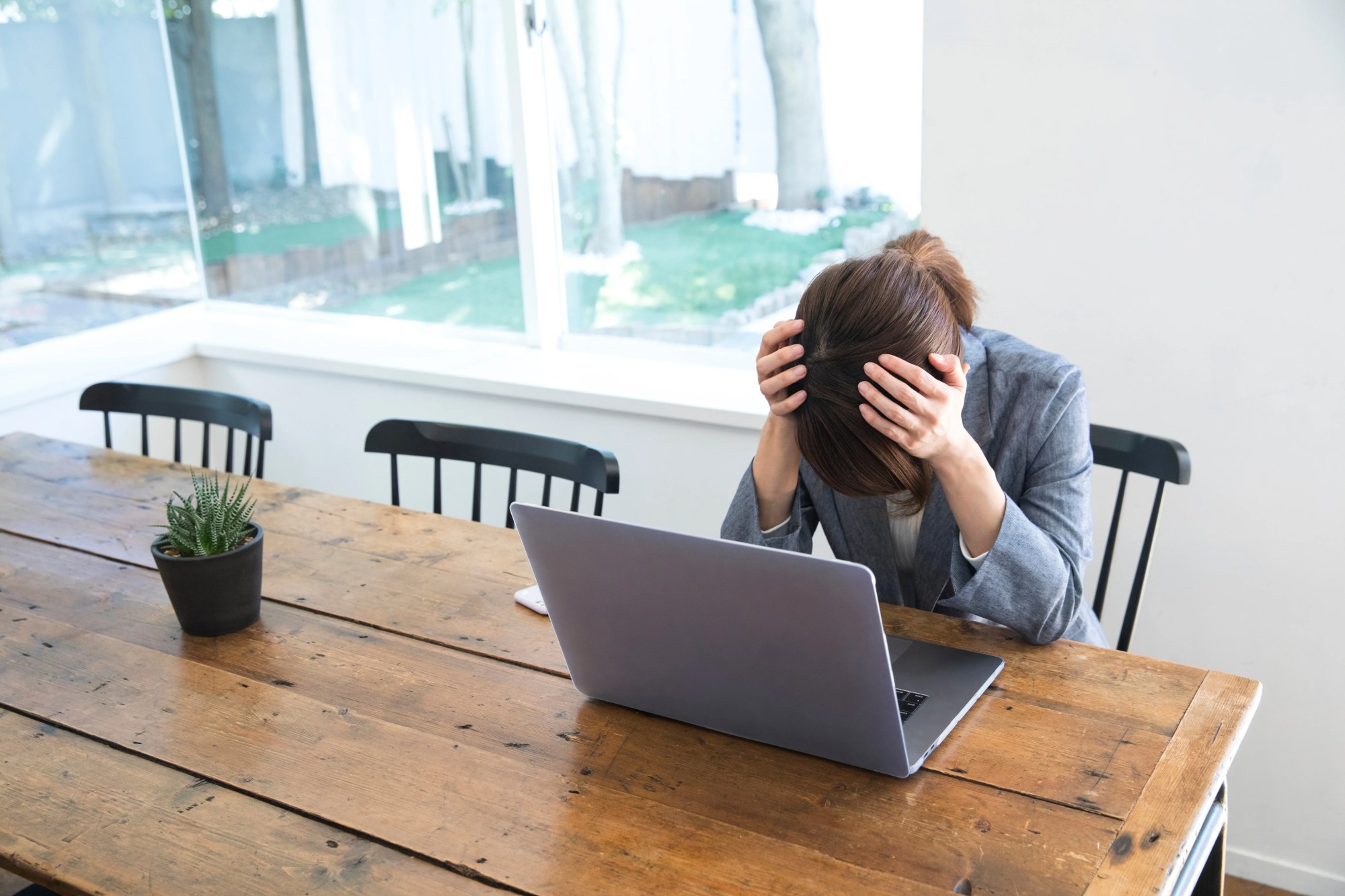 「不調」のイメージ_パソコンの前で頭を抱えて落ち込んでいる様子の女性
