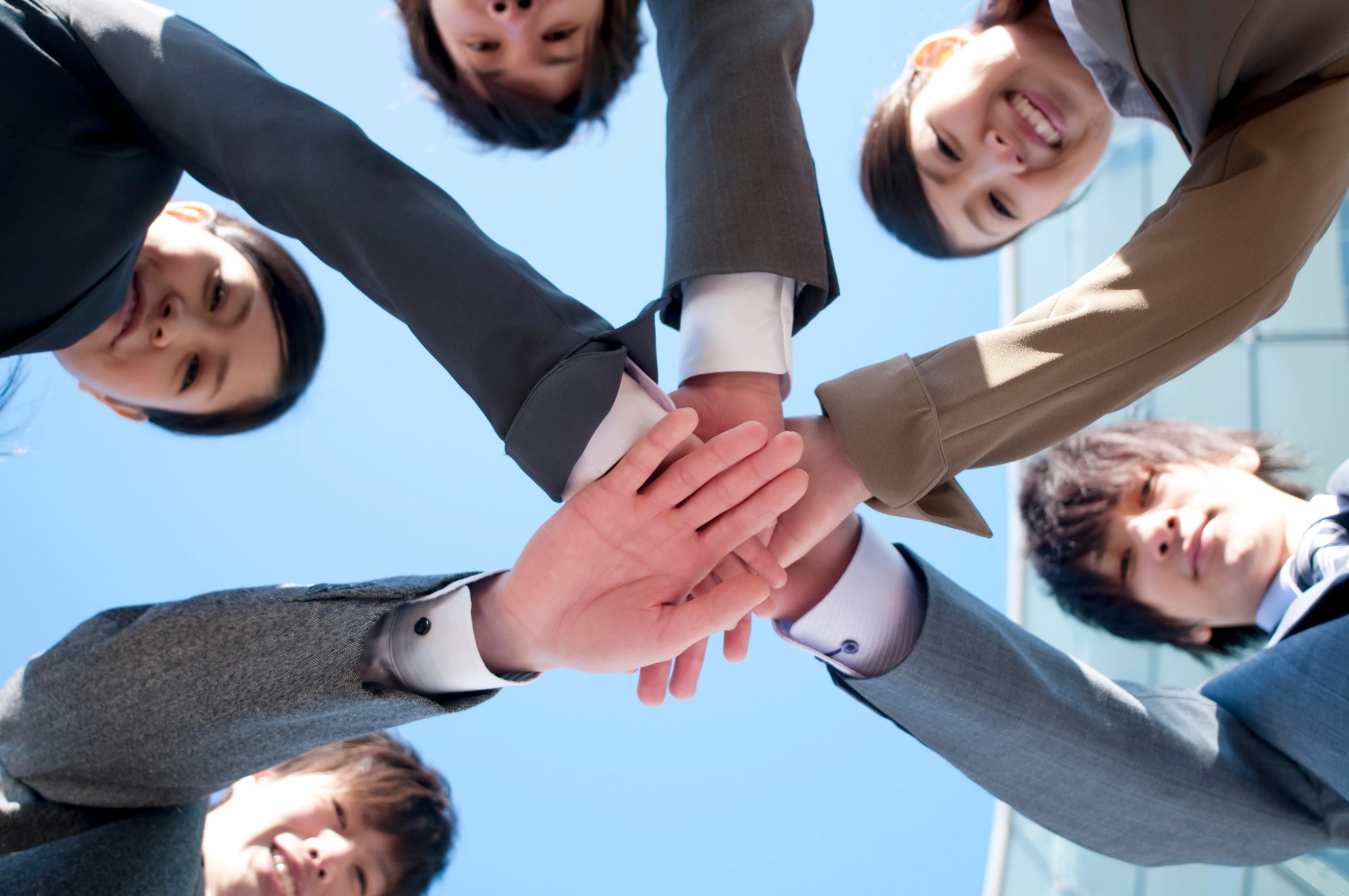 「協力」のイメージ_笑顔で手を合わせる複数名の新入社員