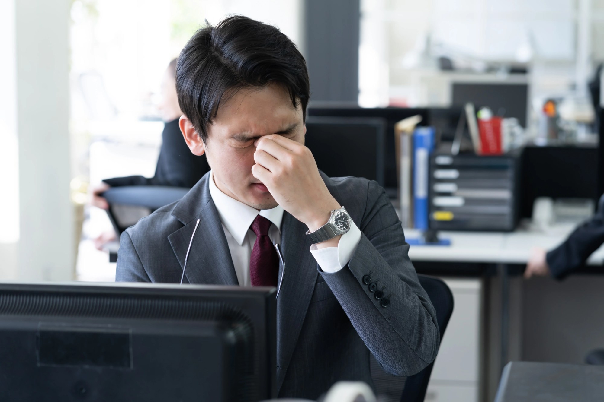 「ストレス」のイメージ_目頭を押さえて辛そうな男性
