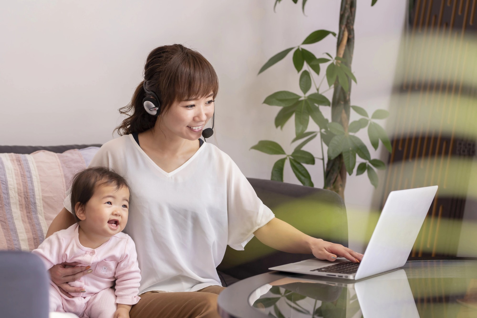 「リモートワーク」のイメージ_女性が赤ちゃんを抱きながら、仕事をしている様子