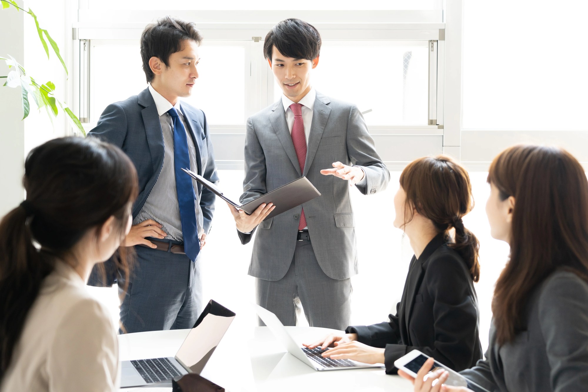 「プレゼン」のイメージ_プレゼンをする男性と、真剣に話を聞く上司と同僚