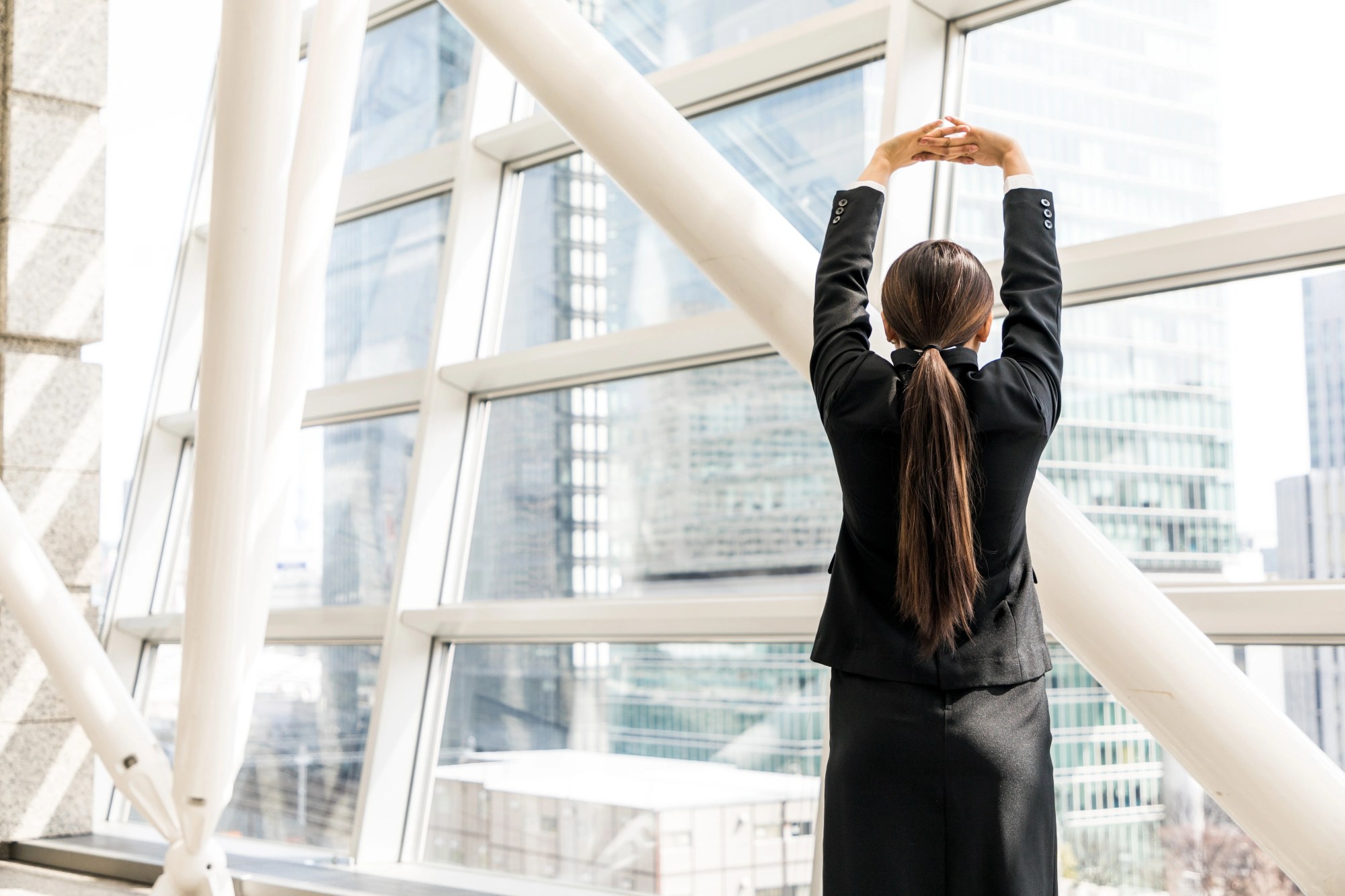「ストレス解消」のイメージ_伸びをして窓の外を見ている女性