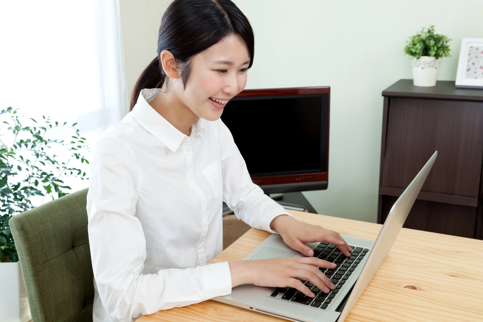 「テレワーク」のイメージ_笑顔でパソコン作業を行う女性