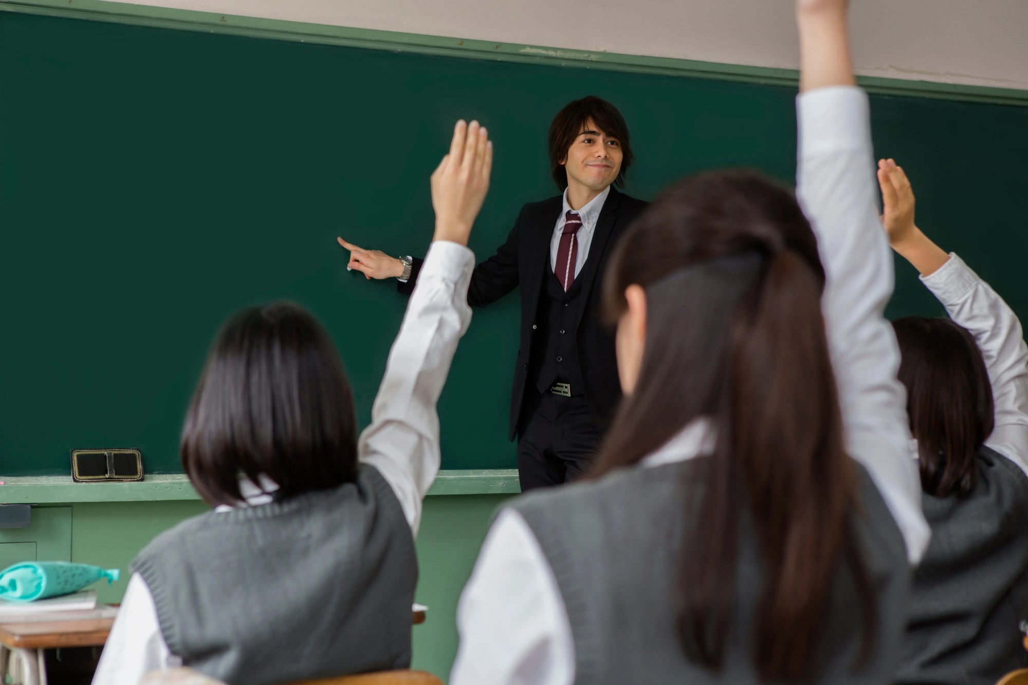「授業」のイメージ_板書する男性教師と、手をあげる学生