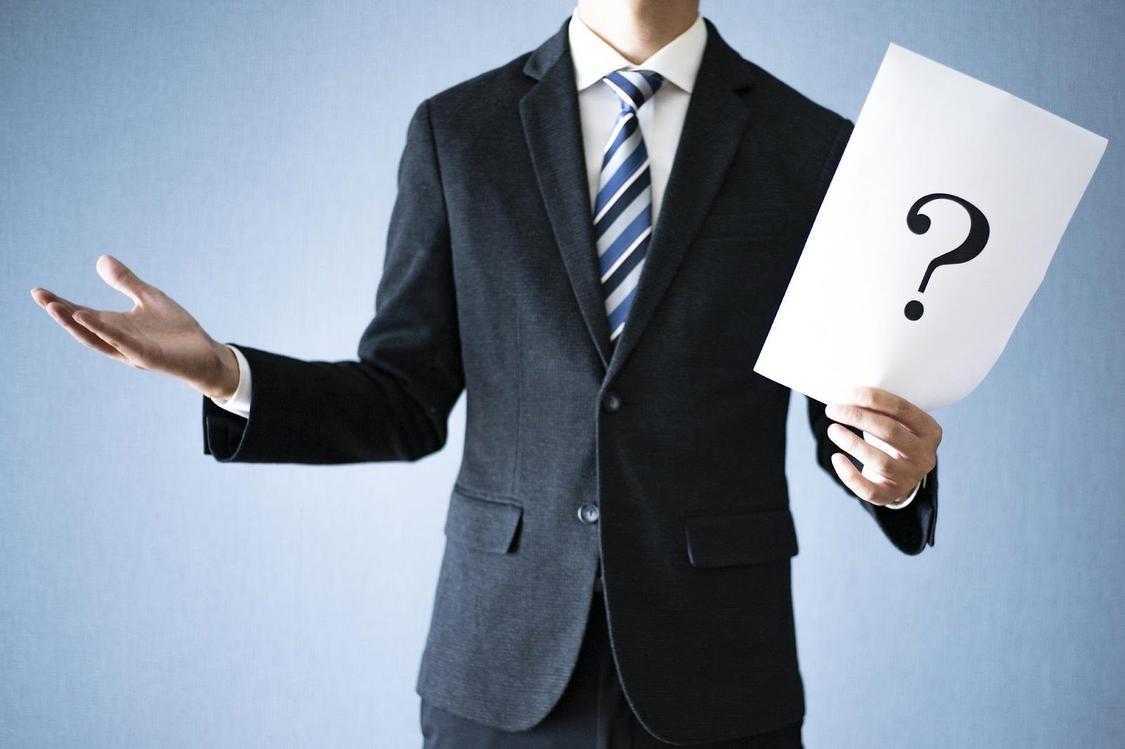「疑問」のイメージ_クエスチョンマークが書かれた紙を持っている男性