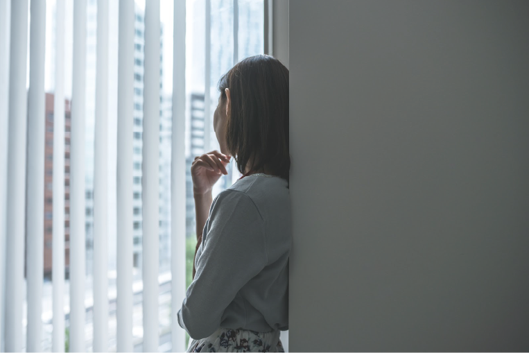 【メンタルヘルス不調】のイメージ_壁にもたれ掛かり悩んでいる様子の女性